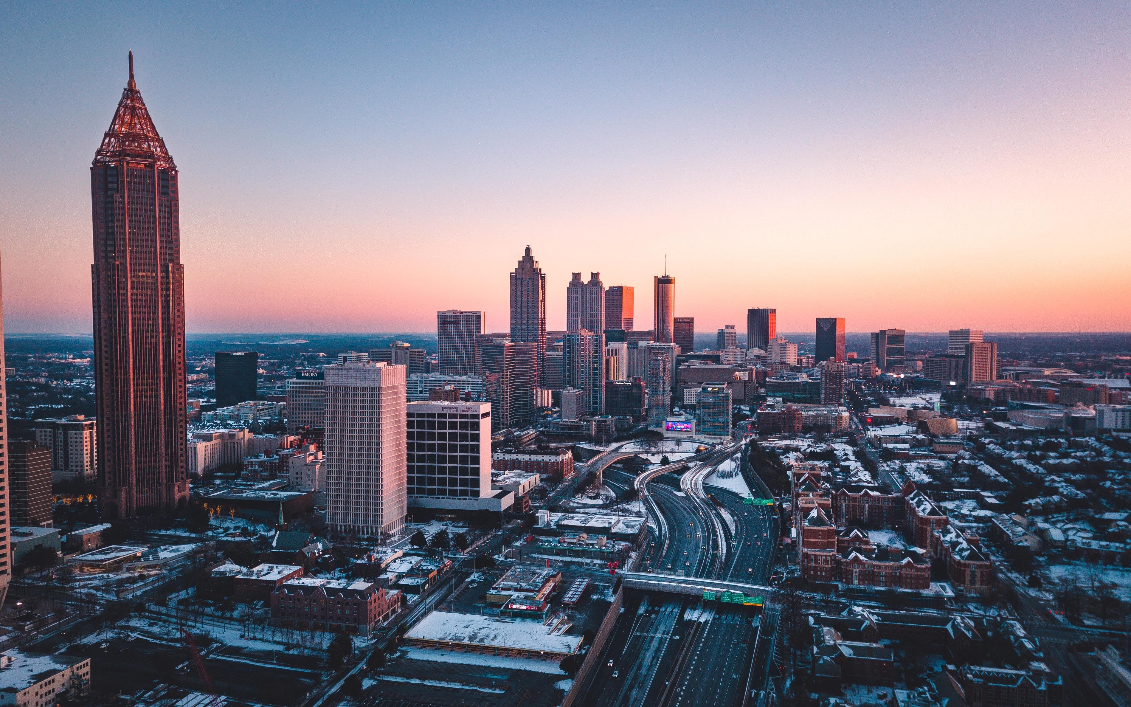 Atlanta skyline and snowy city streets beneath a soft sunset sky